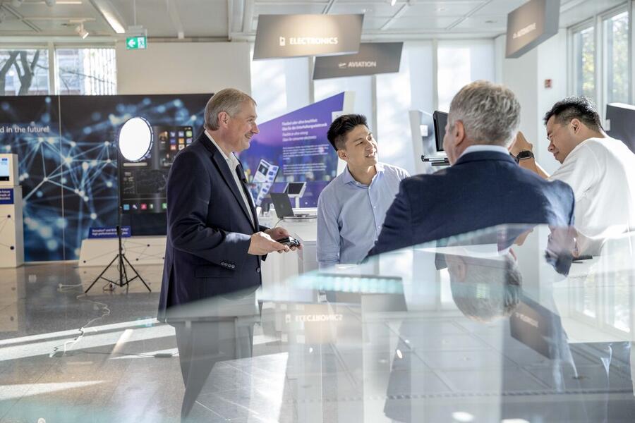 Bin Chen at a technology trade fair, in conversation with industry contacts