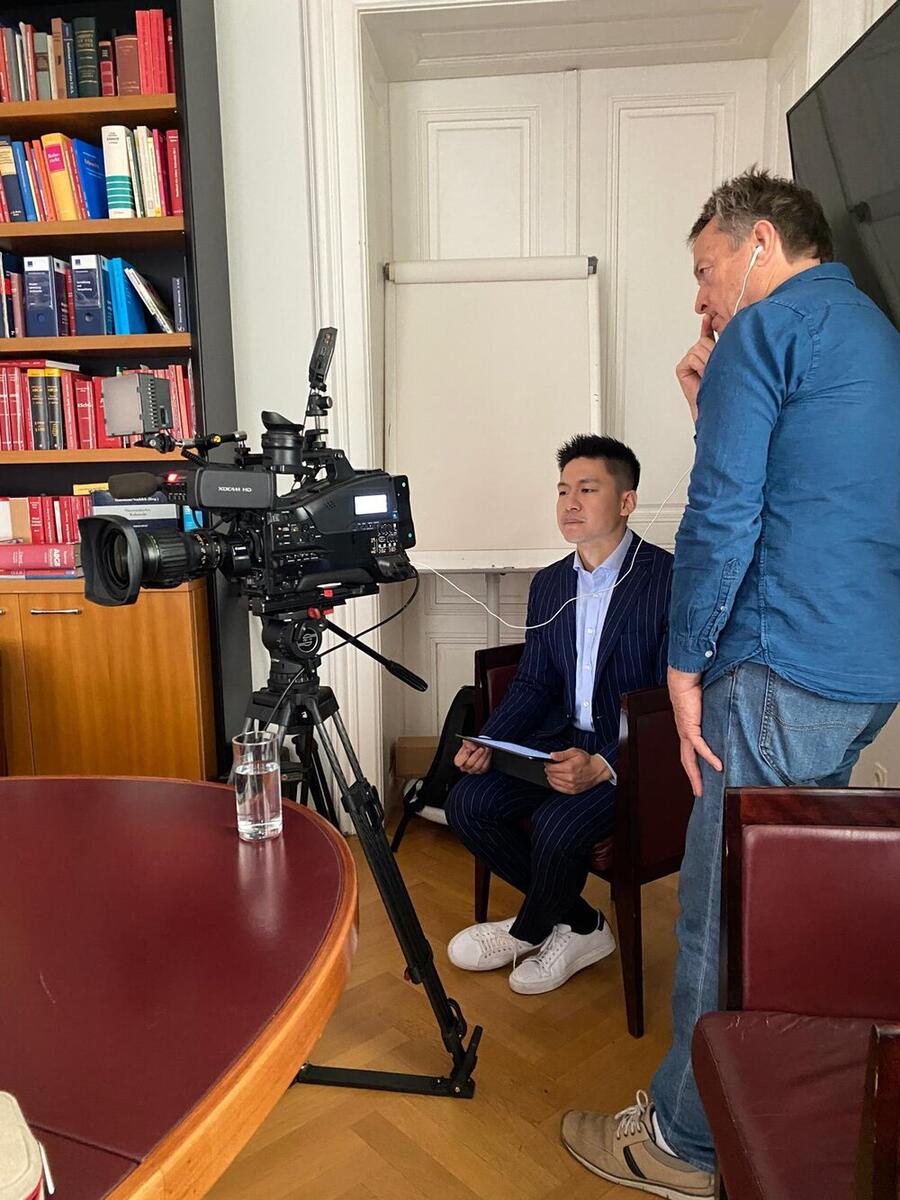 Bin Chen conducting a filmed interview in an office setting